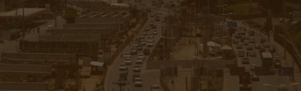 Uma imagem mostrando uma movimentada avenida urbana em Salvador, Bahia, com várias faixas de tráfego congestionado. À esquerda da imagem, há uma construção em andamento com estruturas metálicas e trabalhadores. Ao fundo, prédios comerciais e logos de lojas conhecidas são visíveis, incluindo um McDonald's. A cena destaca o contraste entre a infraestrutura em desenvolvimento e o tráfego intenso típico de uma grande cidade, para ilustrar o artigo sobre IPVA e IPTU.